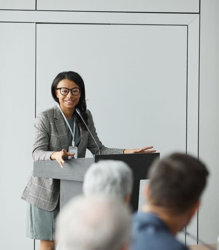 A presenter speaking at a podium in front of an audience