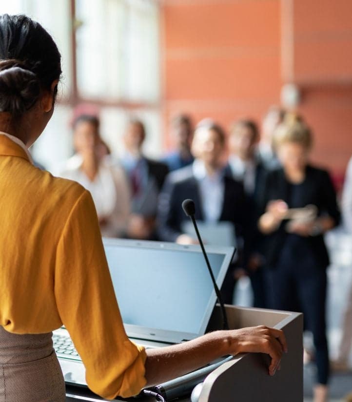 A speaker presenting to an audience from a podium
